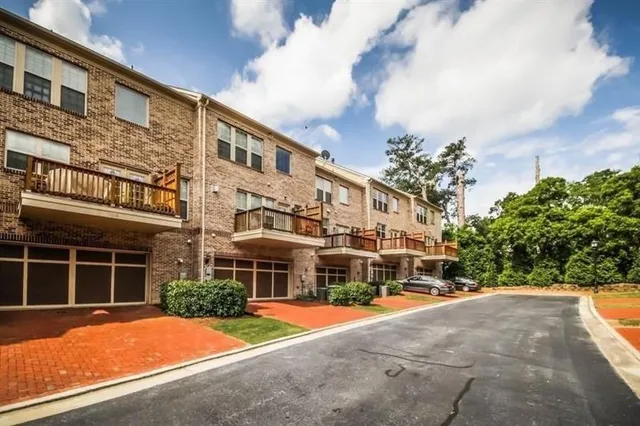a front view of a building with a garden and trees