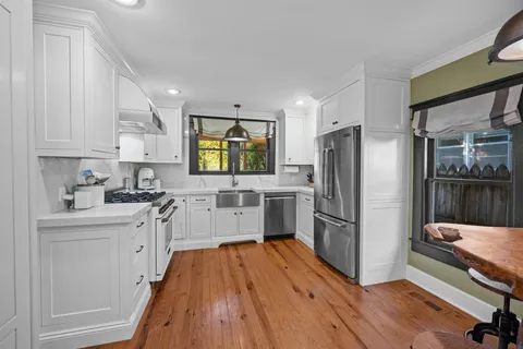 a kitchen with a refrigerator a sink and wooden floor