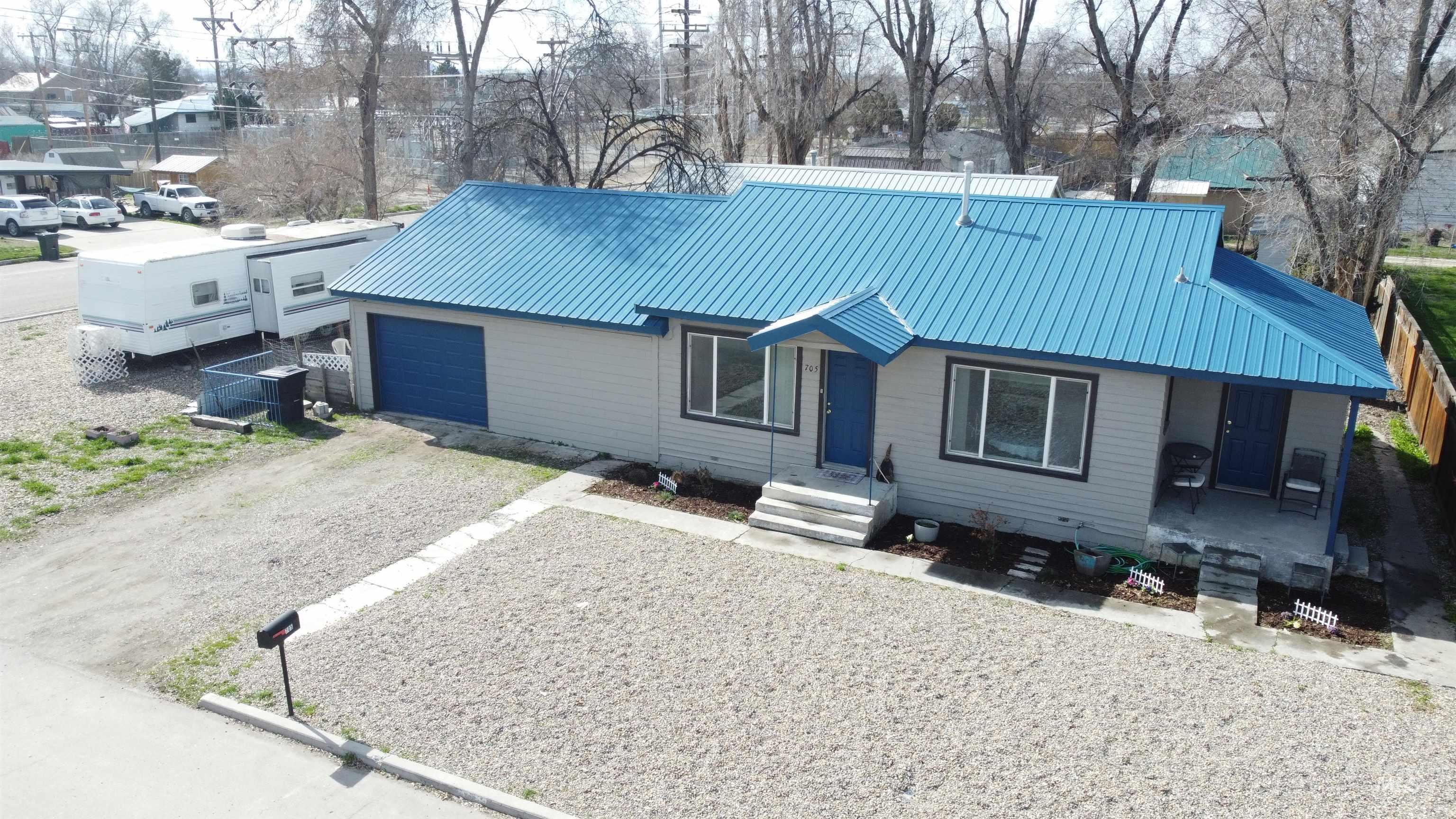 View of front facade featuring driveway, a metal roof, and an attached garage