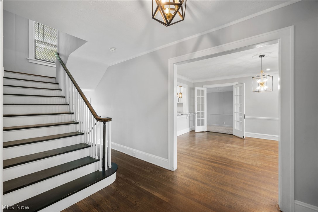 2924 Brighton Road Shaker Heights, OH 44120 - Photo 2 of 31 Stairs with crown molding, a chandelier, wood finished floors, and baseboards
