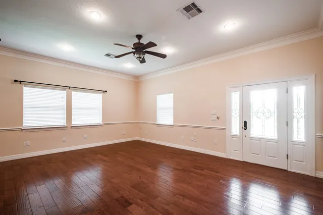 a view of empty room with wooden floor and fan