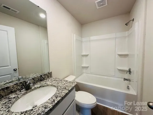 a bathroom with a granite countertop sink a toilet and bathtub