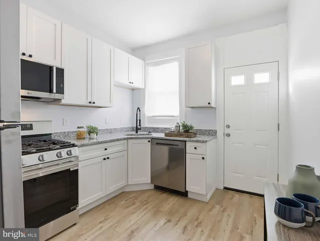 a kitchen with stainless steel appliances white cabinets and a stove top oven