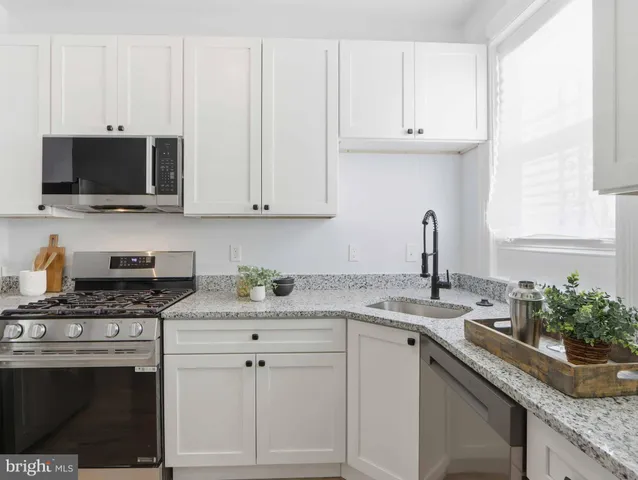 a kitchen with granite countertop white cabinets and a stove