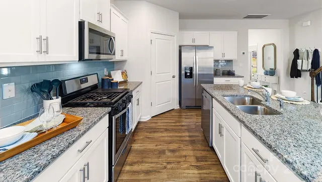 a kitchen with stainless steel appliances granite countertop a sink stove and refrigerator