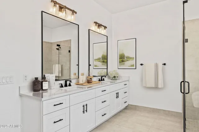 a bathroom with double vanity sink a two mirror a window a glass door and shower