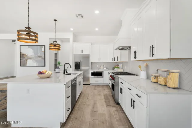 a kitchen with stainless steel appliances granite countertop a sink a stove and a wooden floors