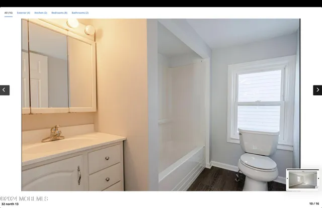 a bathroom with a toilet a sink a mirror and a window