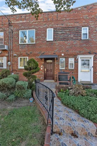 a view of a brick house with a yard and plants