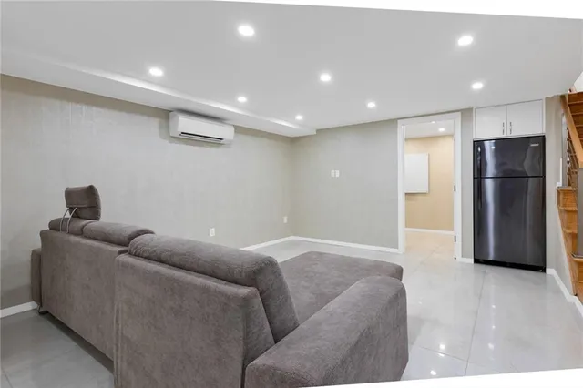 a living room with furniture and a refrigerator