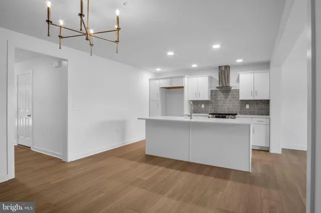 a open kitchen with white cabinets and wooden floor