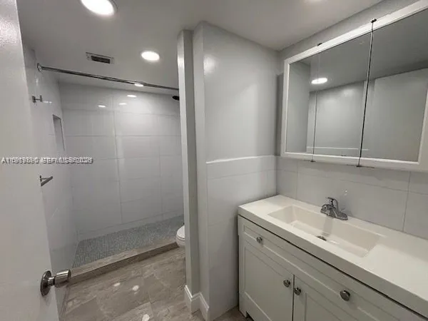 a bathroom with a shower sink vanity and mirror