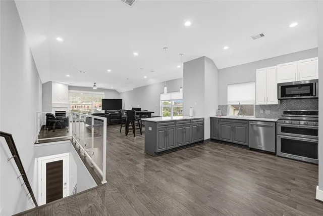 a kitchen with stainless steel appliances kitchen island granite countertop a stove top oven a sink a dining table and chairs