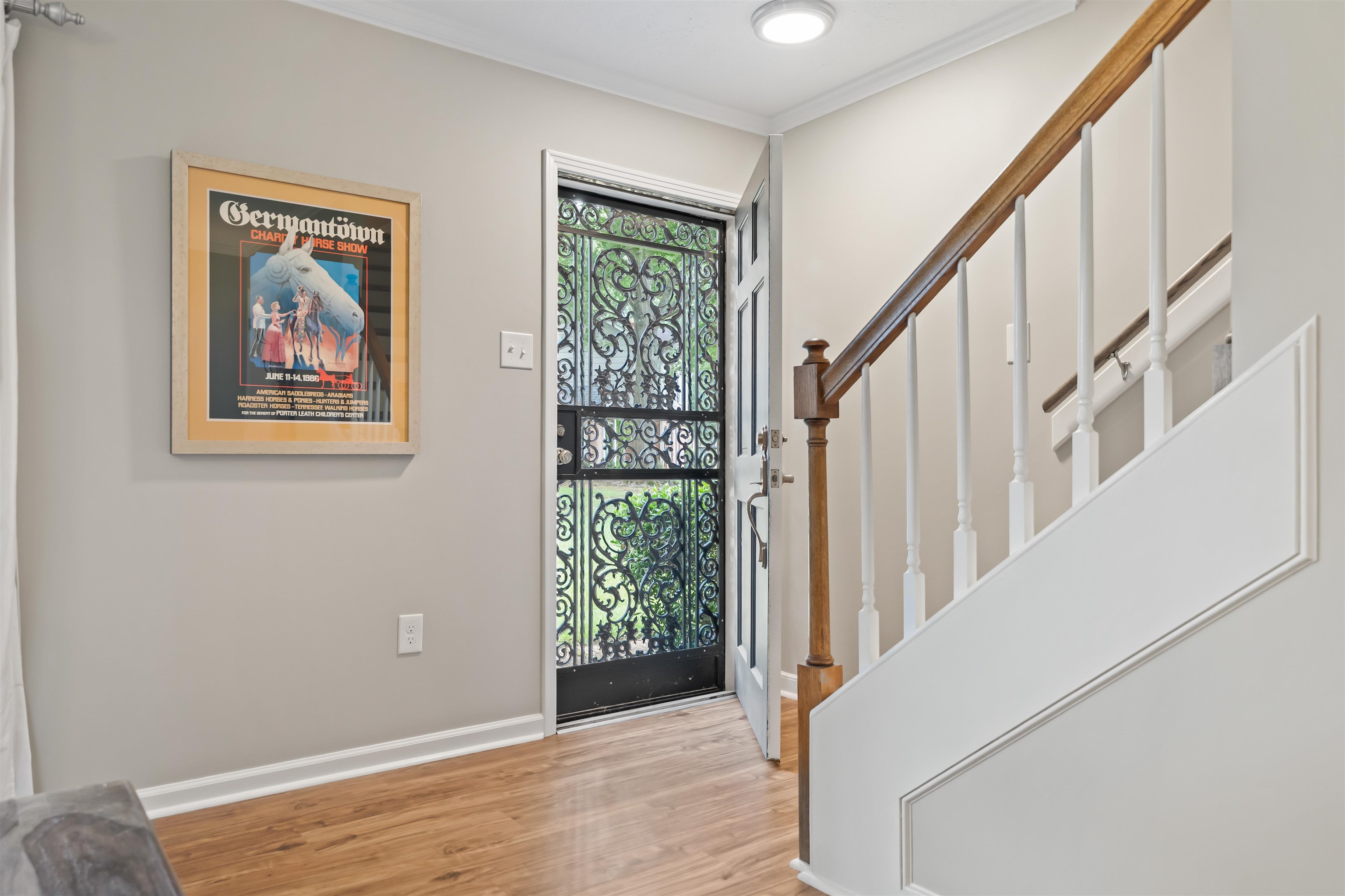6943 Fords Station Road, Unit 64 Germantown, TN 38138 - Photo 4 of 30 Entryway featuring wood-finish flooring, a decorative security screen door, and a staircase with a wooden handrail and white balusters
