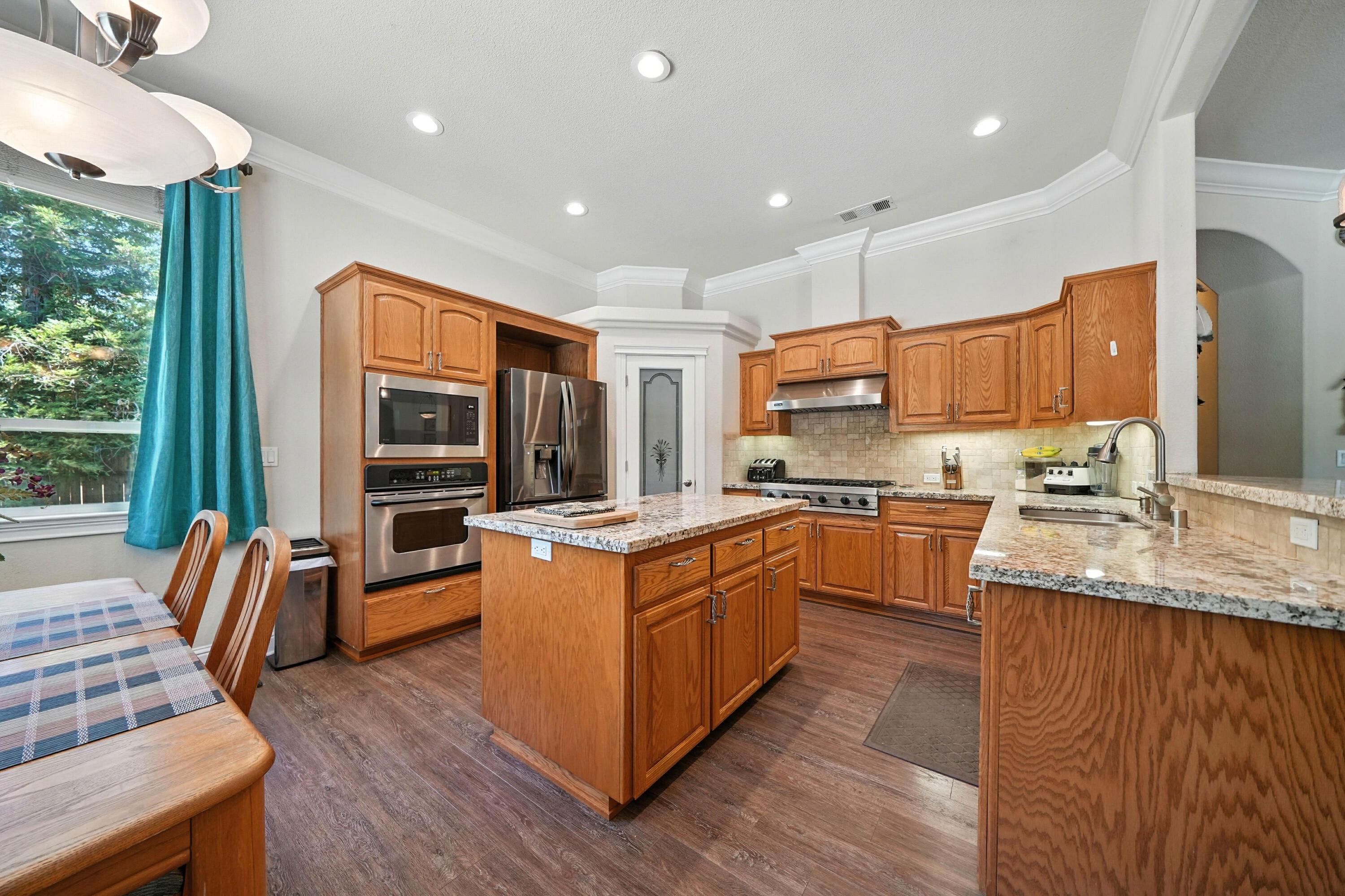 7777 Pit Road Redding, CA 96001 - Photo 7 of 27 a large kitchen with stainless steel appliances granite countertop a stove a sink dishwasher a refrigerator white cabinets wooden floor and a large window