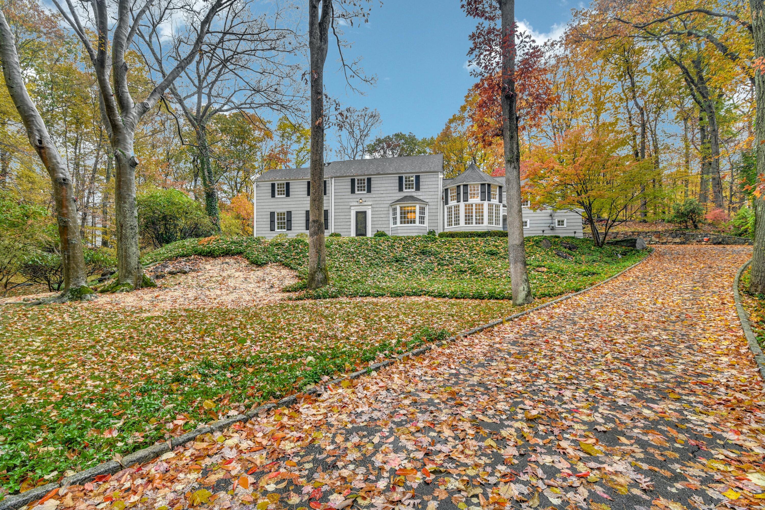 a view of a white house with a yard and large trees