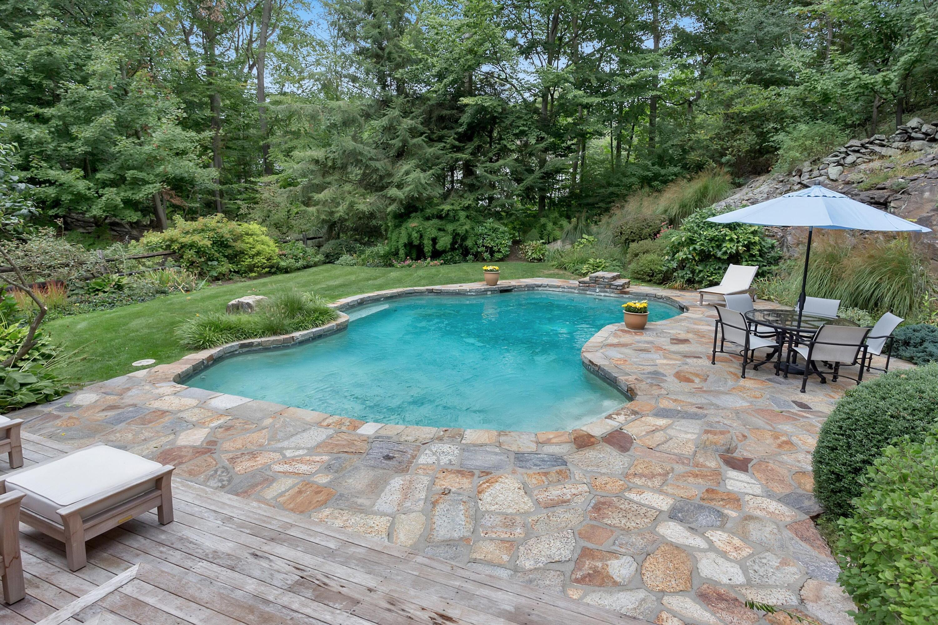 22 Stony Brook Road Darien, CT 06820 - Photo 32 of 33 a view of a swimming pool with lawn chairs under an umbrella