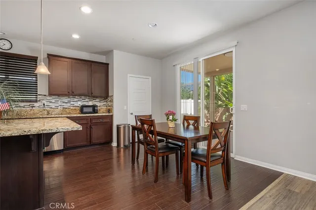 a kitchen with stainless steel appliances kitchen island granite countertop wooden floor dining table and chairs