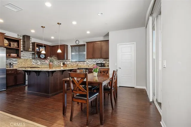 a kitchen with stainless steel appliances kitchen island granite countertop wooden floor cabinets and a dining table