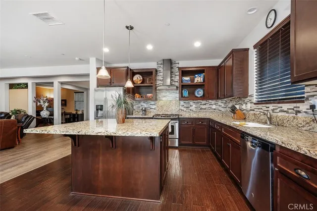 a large kitchen with stainless steel appliances kitchen island granite countertop a large stove a sink dishwasher and cabinets with wooden floor