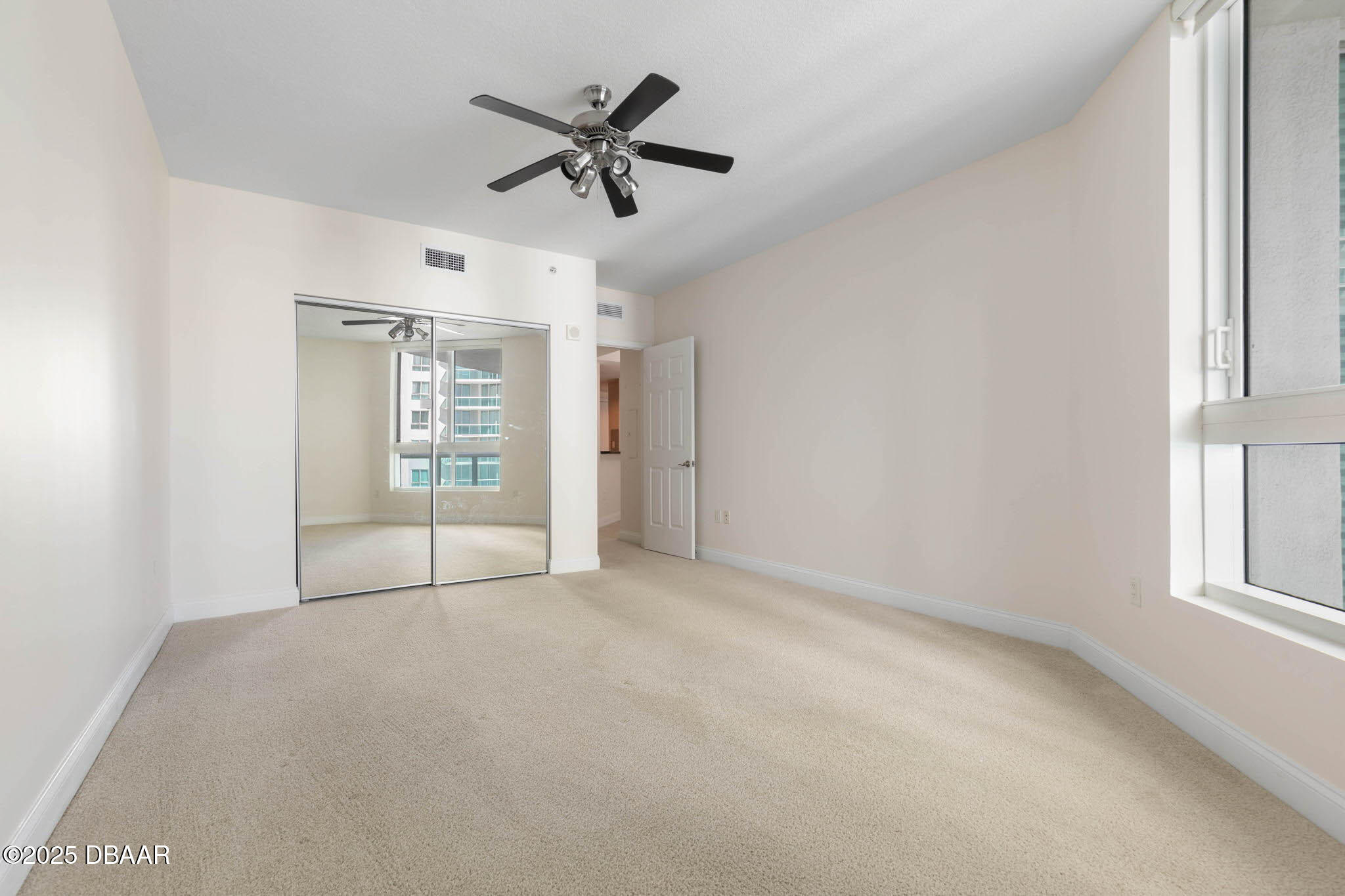 231 Riverside Drive, Unit 608 Holly Hill, FL 32117 - Photo 36 of 74 an empty room with chandelier fan and windows