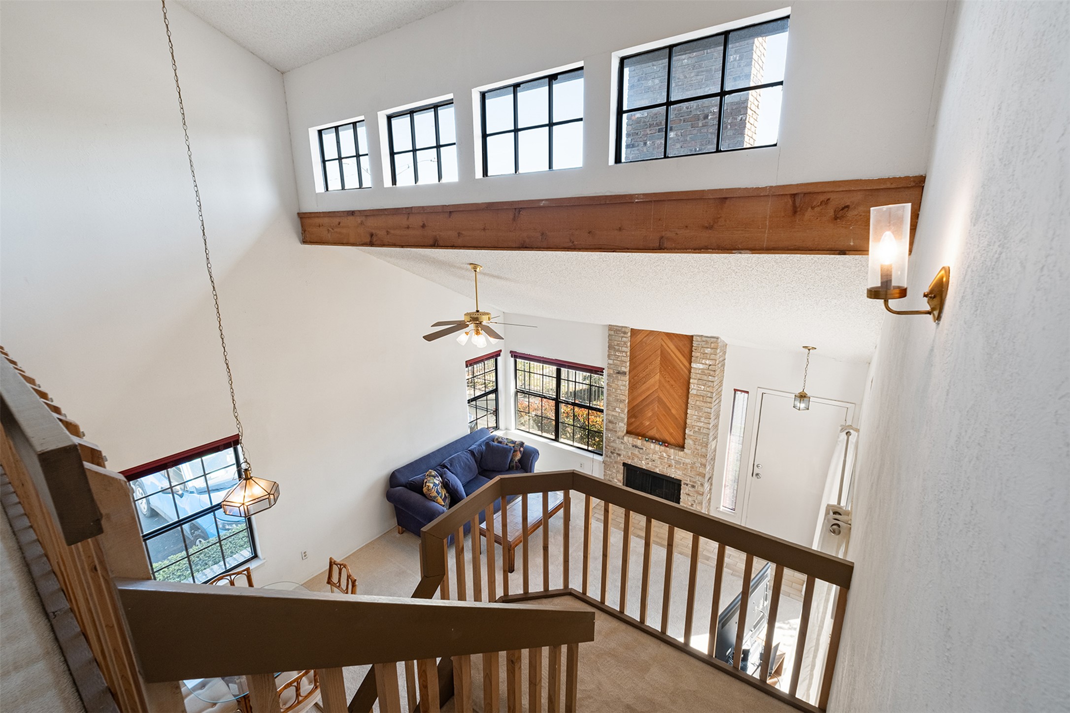 1748 Ohlen Road, Unit 16 Austin, TX 78757 - Photo 30 of 38 Stairway featuring a large fireplace, carpet floors, a ceiling fan, and a high textured ceiling