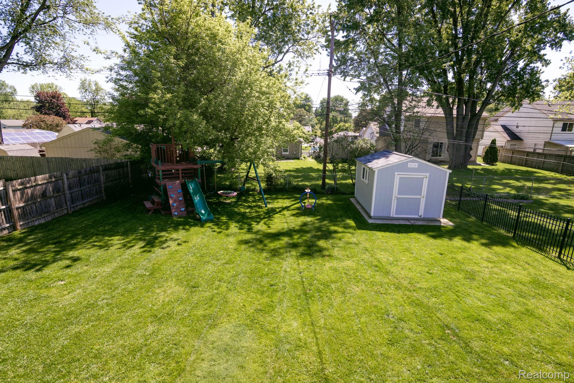 3757 Cone Avenue Rochester, MI 48309 - Photo 43 of 45 Expansive backyard featuring a large green lawn, a light blue storage shed, a wood fence, and mature trees providing natural shade