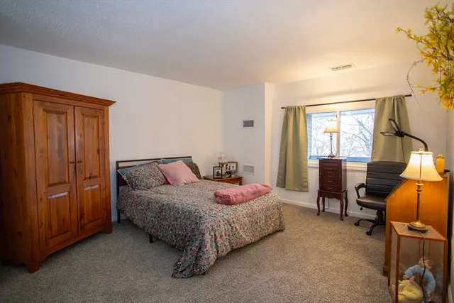 a bedroom with a bed chair and mirror