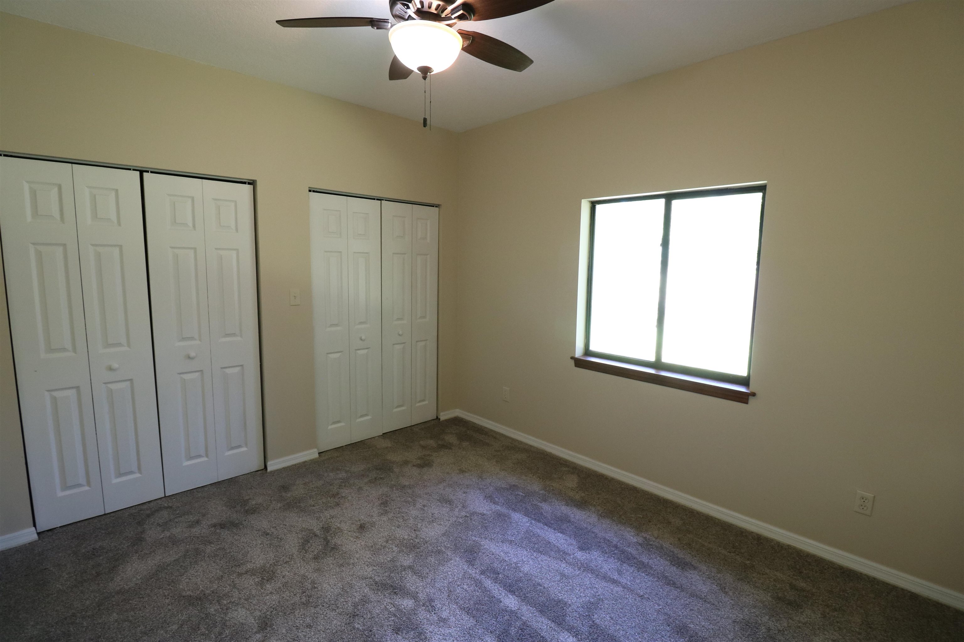 5861 Datil Pepper Road St. Augustine, FL 32086 - Photo 20 of 27 Unfurnished bedroom featuring multiple closets, dark carpet, and a ceiling fan