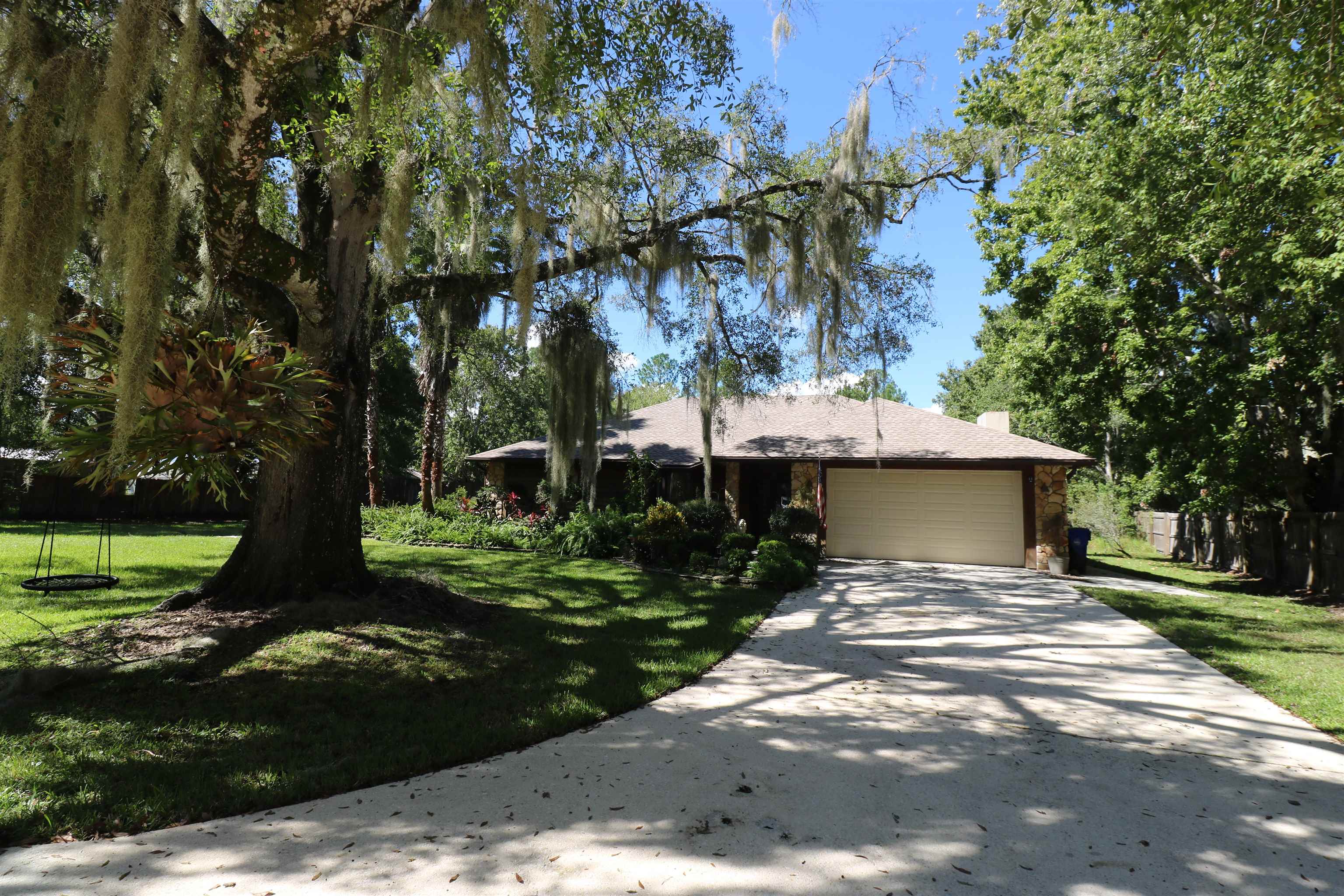 5861 Datil Pepper Road St. Augustine, FL 32086 - Photo 3 of 27 View of front facade featuring an attached garage, concrete driveway, a front yard, and a chimney