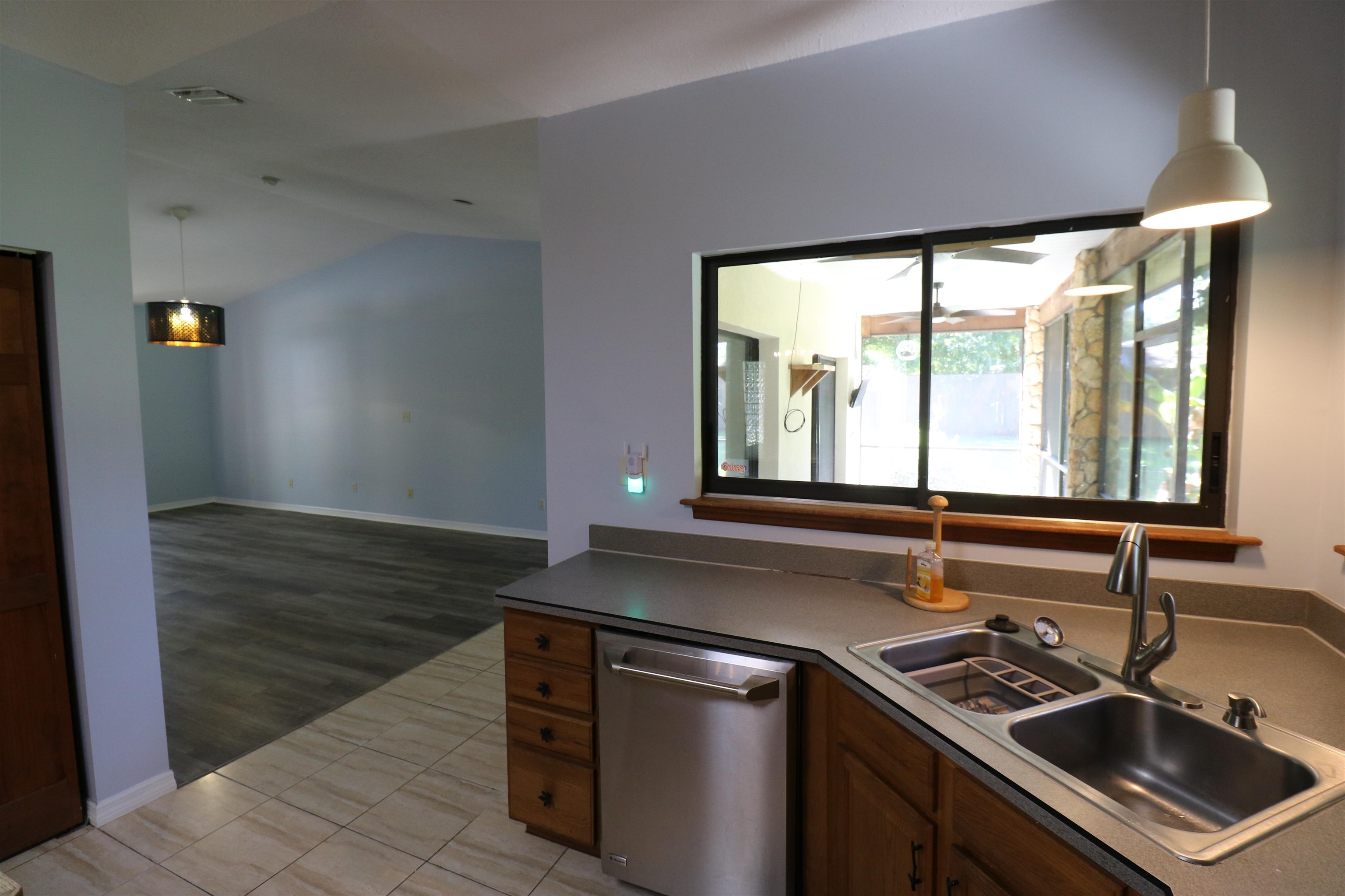 5861 Datil Pepper Road St. Augustine, FL 32086 - Photo 9 of 27 Kitchen featuring decorative light fixtures, dark countertops, stainless steel dishwasher, light tile patterned flooring, and lofted ceiling