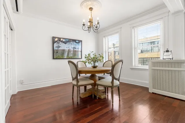 a dining room with wooden floor a chandelier a wooden table and chairs