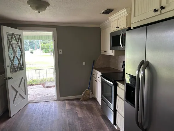 a kitchen with stainless steel appliances granite countertop a refrigerator a stove and a wooden floors