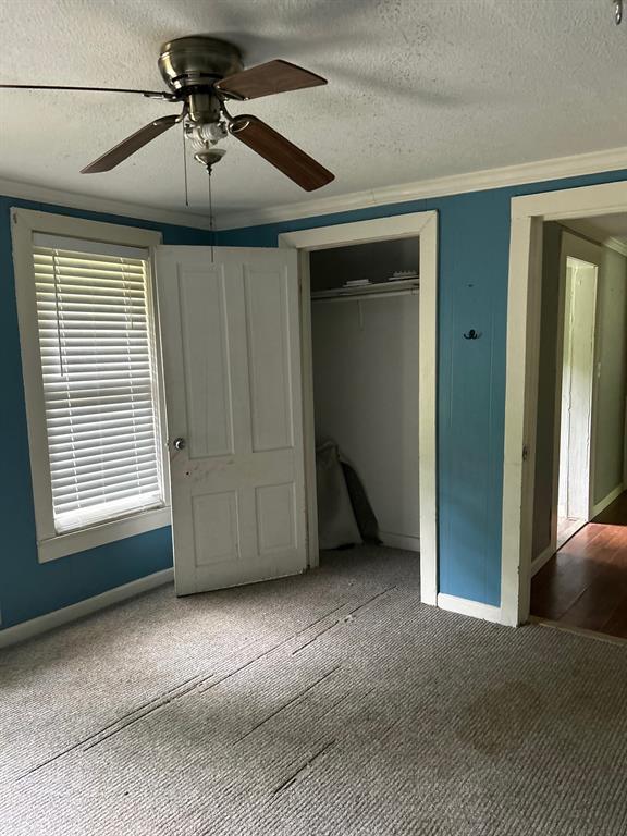 1330 Palmetto Road Benton, LA 71006 - Photo 8 of 13 Unfurnished bedroom with a textured ceiling, a ceiling fan, carpet, a closet, and crown molding