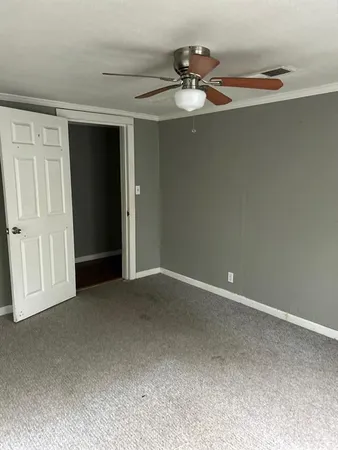 a view of an empty room and chandelier fan