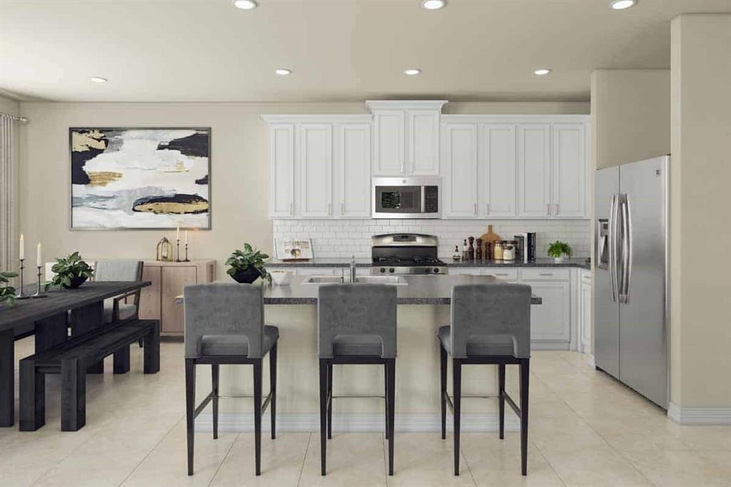 a kitchen with stainless steel appliances granite countertop a table chairs and a refrigerator