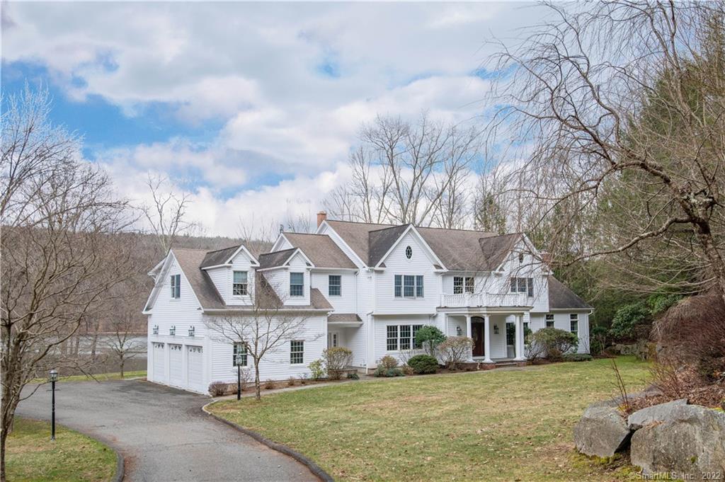 a view of a white house with a big yard and large trees