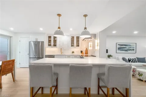 a kitchen with stainless steel appliances a dining table chairs and white cabinets