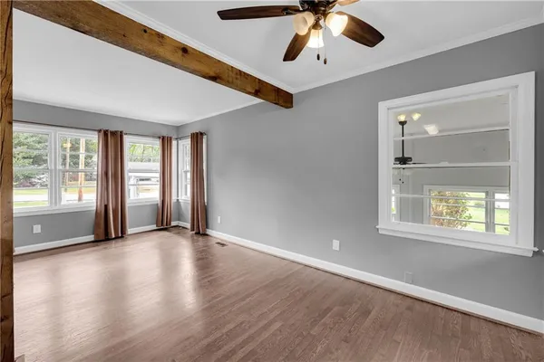 a view of an empty room with a window and wooden floor