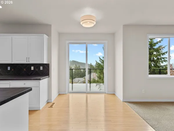 a view of an empty room with a window and a kitchen