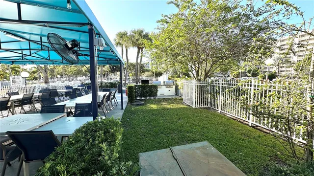 a view of a patio with table and chairs potted plants and large tree