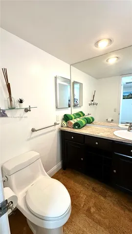 a bathroom with a granite countertop toilet sink and mirror