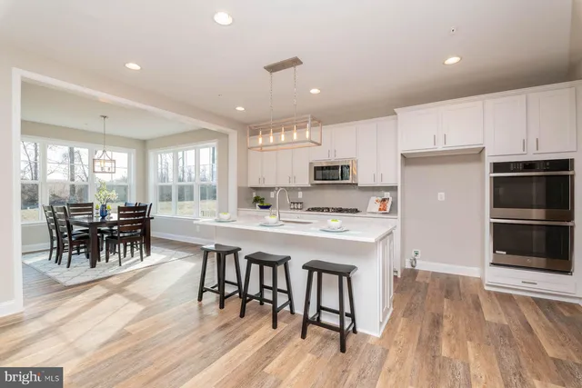 a kitchen with stainless steel appliances a dining table chairs stove and cabinets