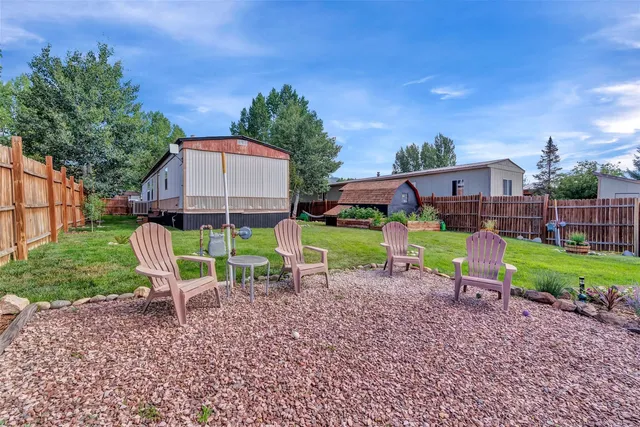 a view of a chair and table in backyard of the house