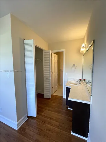 a view of an empty room with wooden floor and a bathroom