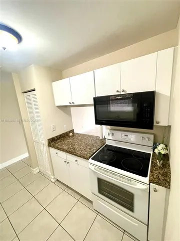 a kitchen with granite countertop a stove and a white refrigerator