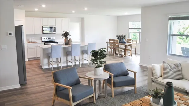 a dining room with furniture wooden floor and a kitchen view