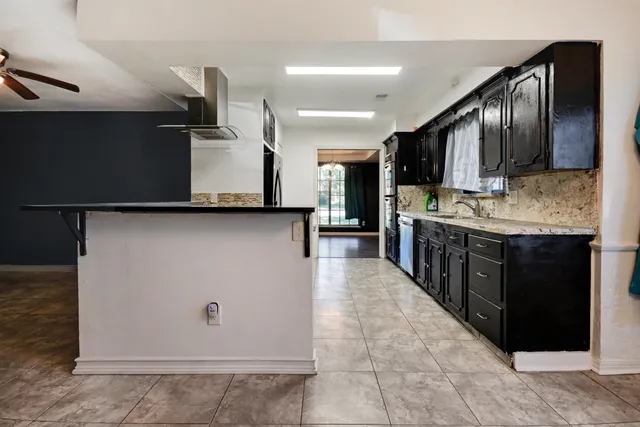 a large kitchen with stainless steel appliances a sink a stove and cabinets