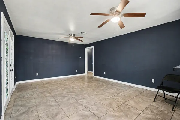a view of an empty room with a ceiling fan and window