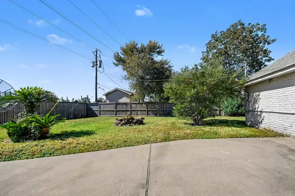 a white house with a big yard and large trees with wooden fence